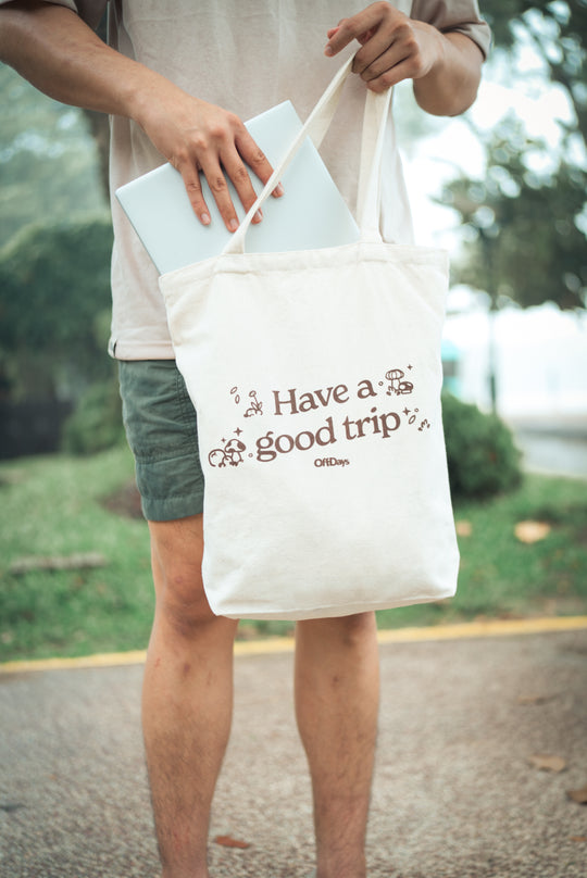 man pulling a laptop from a tote bag which says have a good trip