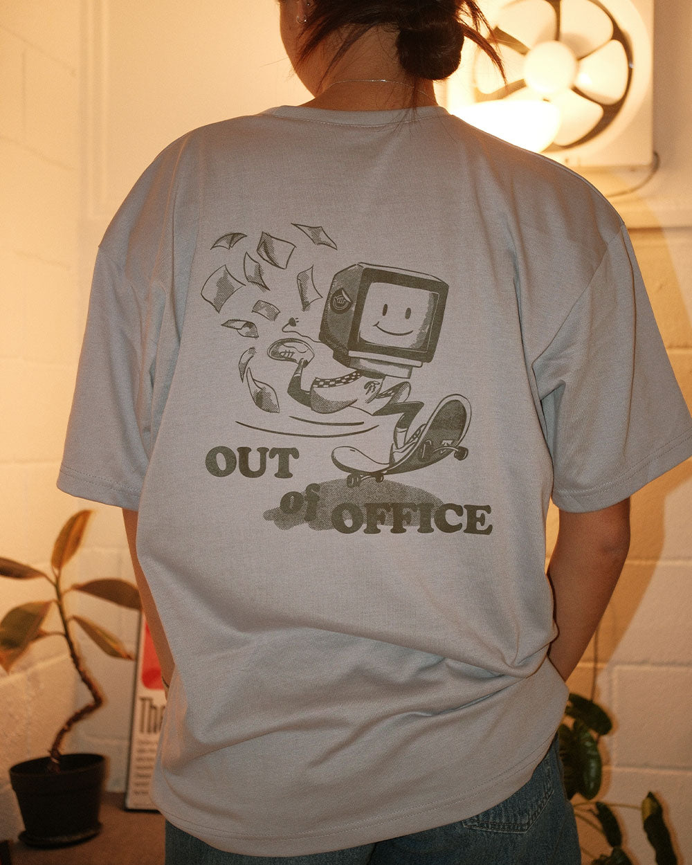 back of a grey graphic t shirt that says out of office